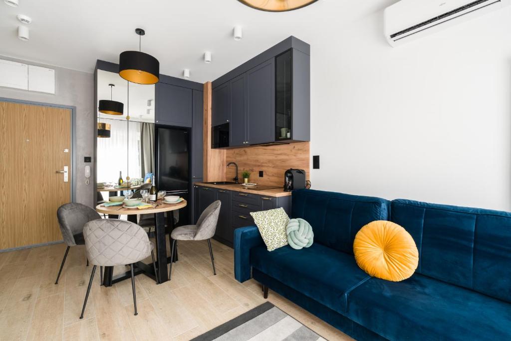 a living room with a blue couch and a kitchen at Niedziałkowskiego 25 Apartments Stary Browar City Center by Renters Prestige in Poznań