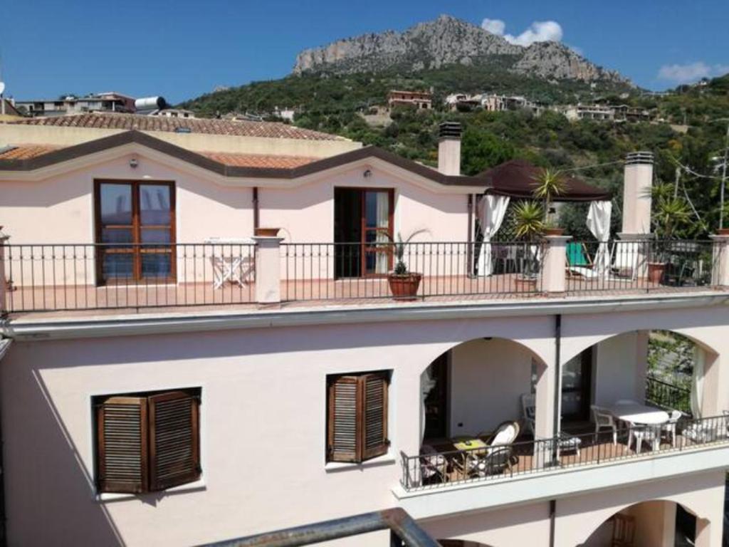 Casa con balcón con una montaña en el fondo en attico panoramico sul mare, en Santa Maria Navarrese
