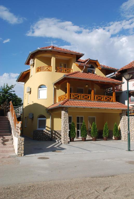 une grande maison jaune avec un balcon au-dessus dans l'établissement Vila Simic Srebrno Jezero, à Ostrovo