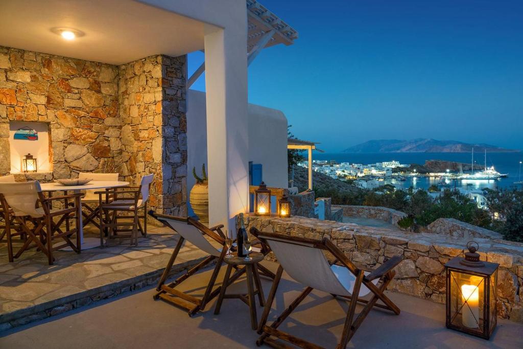 un patio con mesa, sillas y pared de piedra. en Sirocos, en Karavostasi