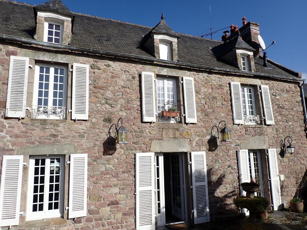 a building with white shuttered windows and people on the roof at La Capitainerie, la plage à 5 minutes à pied ! in Fréhel