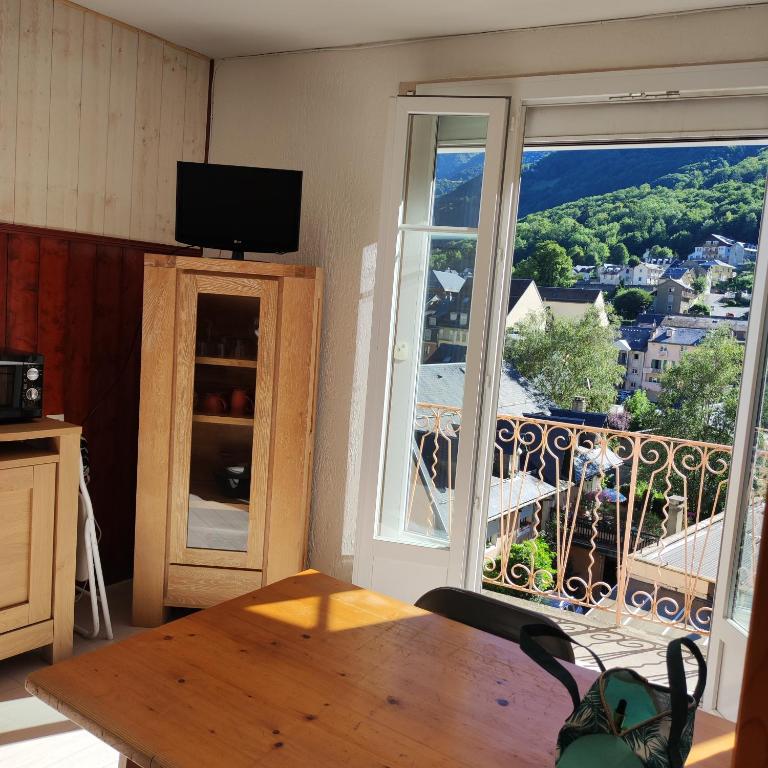 un salon avec une table et une grande fenêtre dans l'établissement Hyper centre, excellent emplacement, à Cauterets