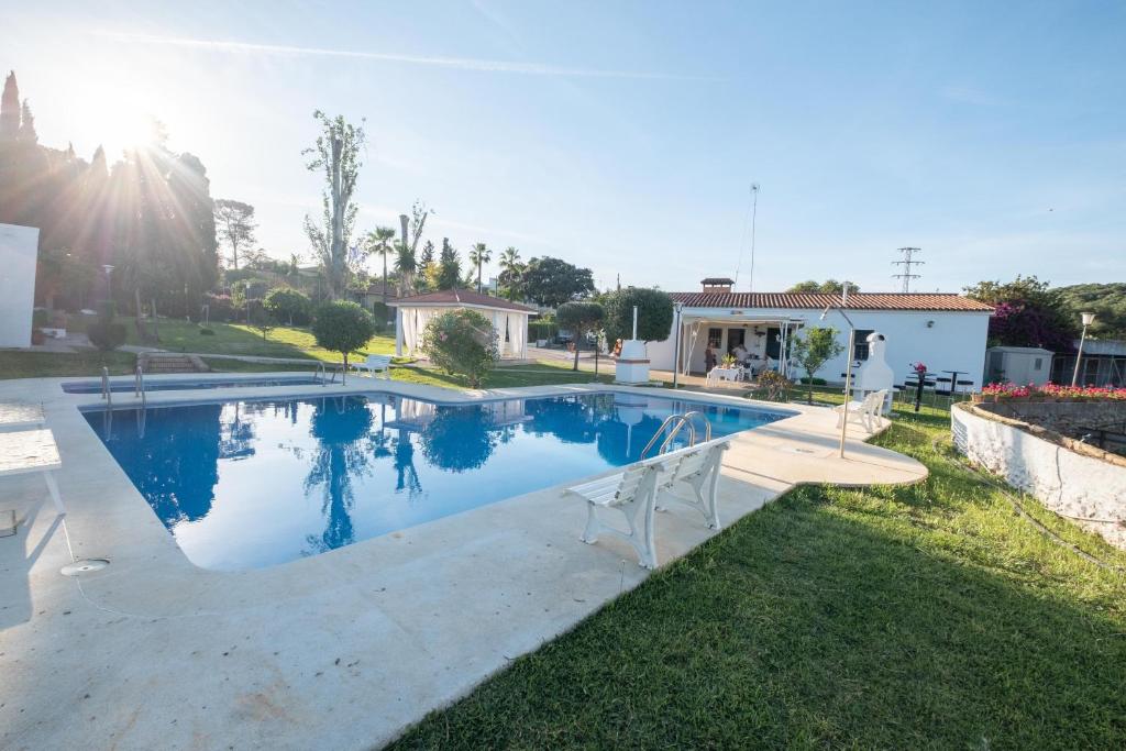 uma piscina com duas cadeiras num quintal em Agradable Villa con piscina em Sevilha