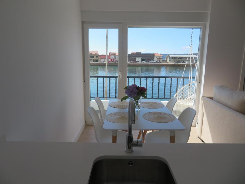 a kitchen with a sink and a table and a balcony at Apartamento Centinela Do Mar in O Pindo