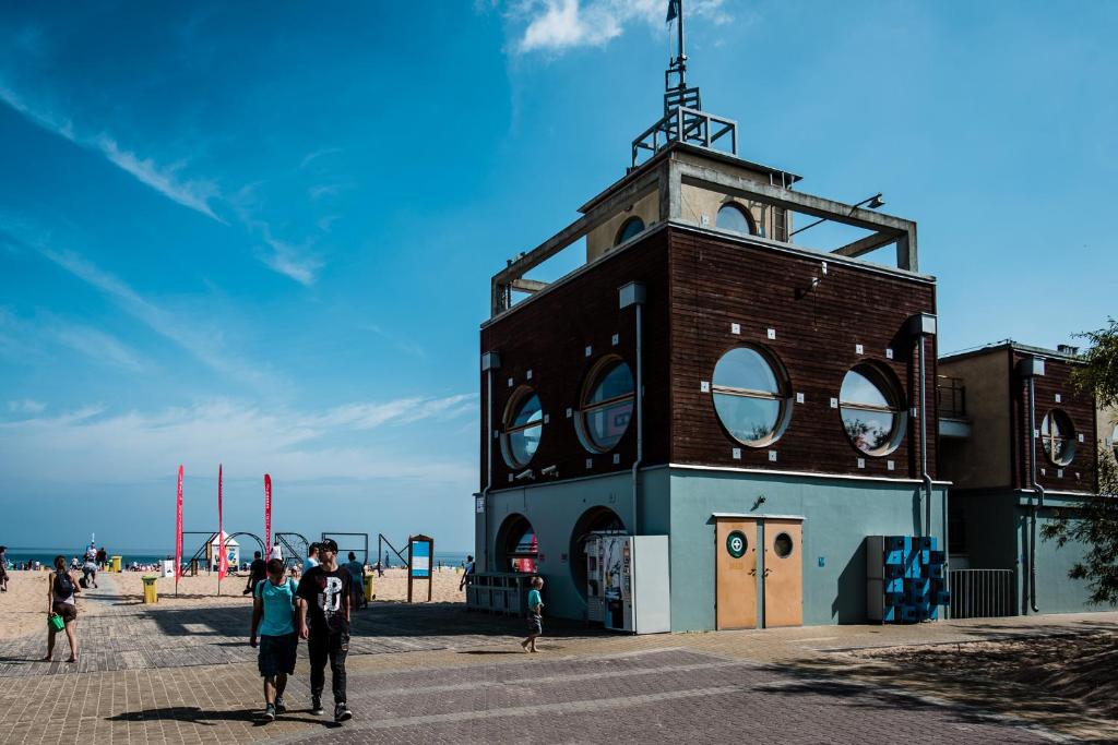 dos personas caminando por una torre del reloj en la playa en Apartament Gdańsk Stogi Plaża, en Gdansk