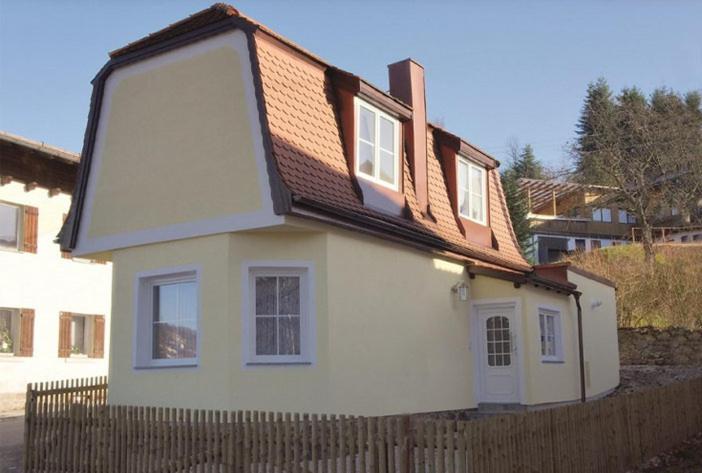 una piccola casa bianca con una recinzione in legno di Ferienhaus Lohberg a Lohberg