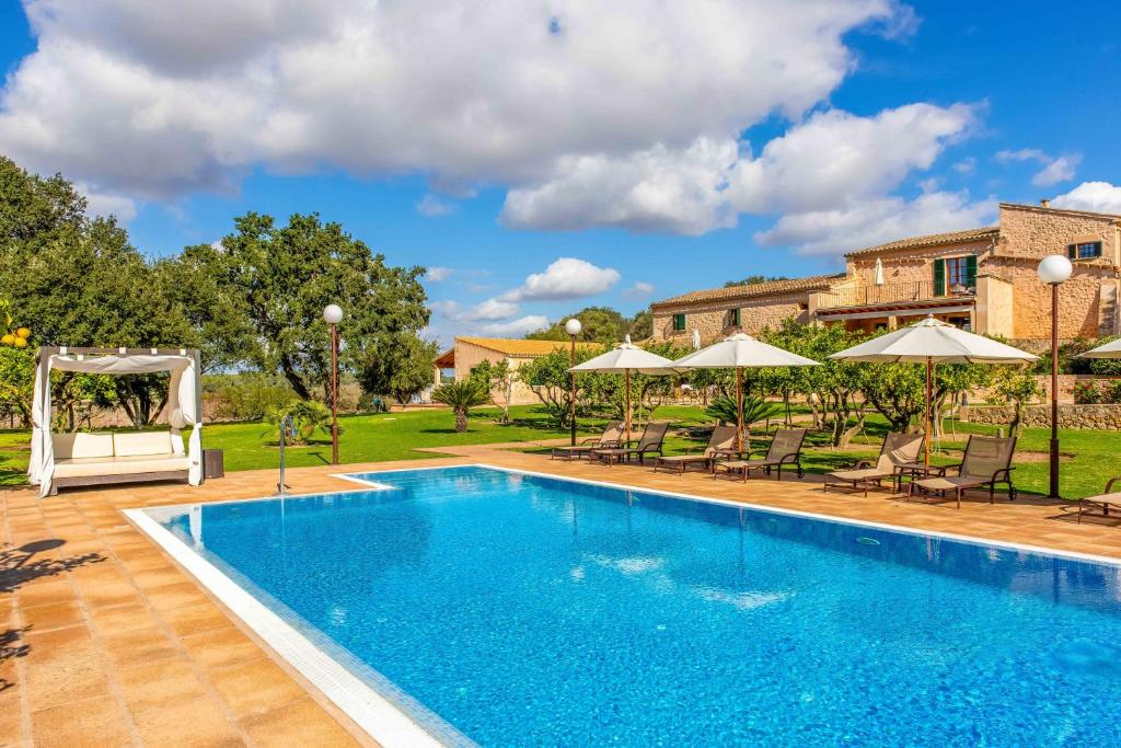 a pool with chairs and umbrellas next to a house at Finca Son Roig by Valentin in Porreres