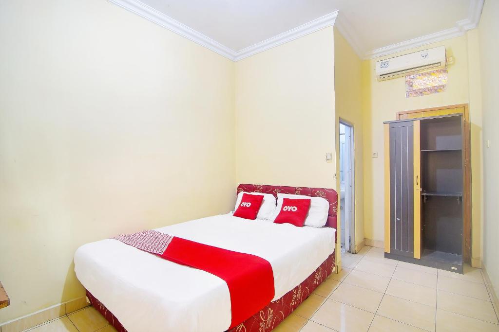 a bedroom with a bed with red and white pillows at OYO 90463 A2b Guesthouse in Manado