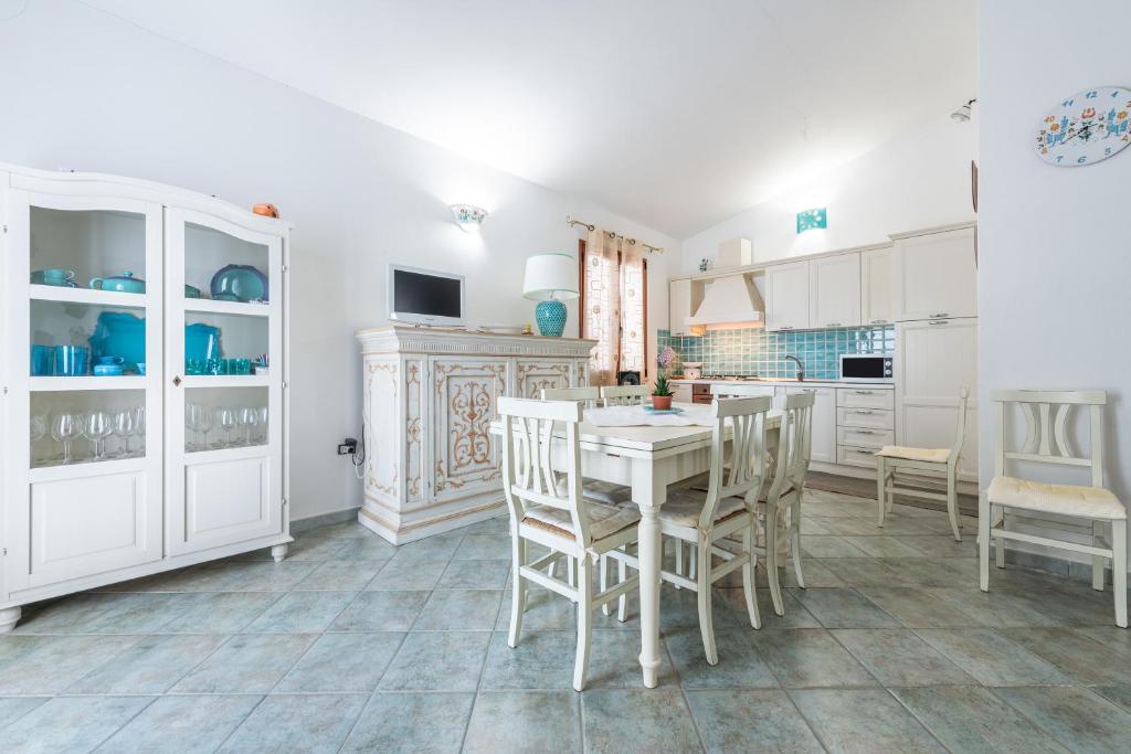 a kitchen with white cabinets and a table and chairs at Villa Chiara in SantʼAntìoco