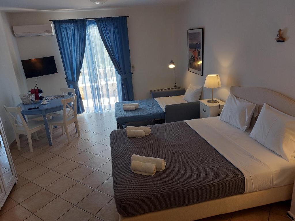 a hotel room with two beds and a table and a desk at PLEIADES lUXURY APARTMENTS in Porto Heli