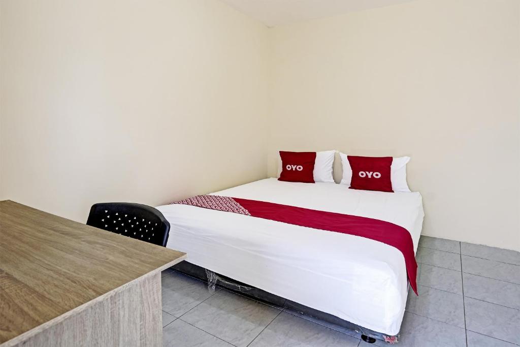 a bedroom with a large bed and a desk at OYO 3285 Wonoayu Residence Syariah in Sidoarjo