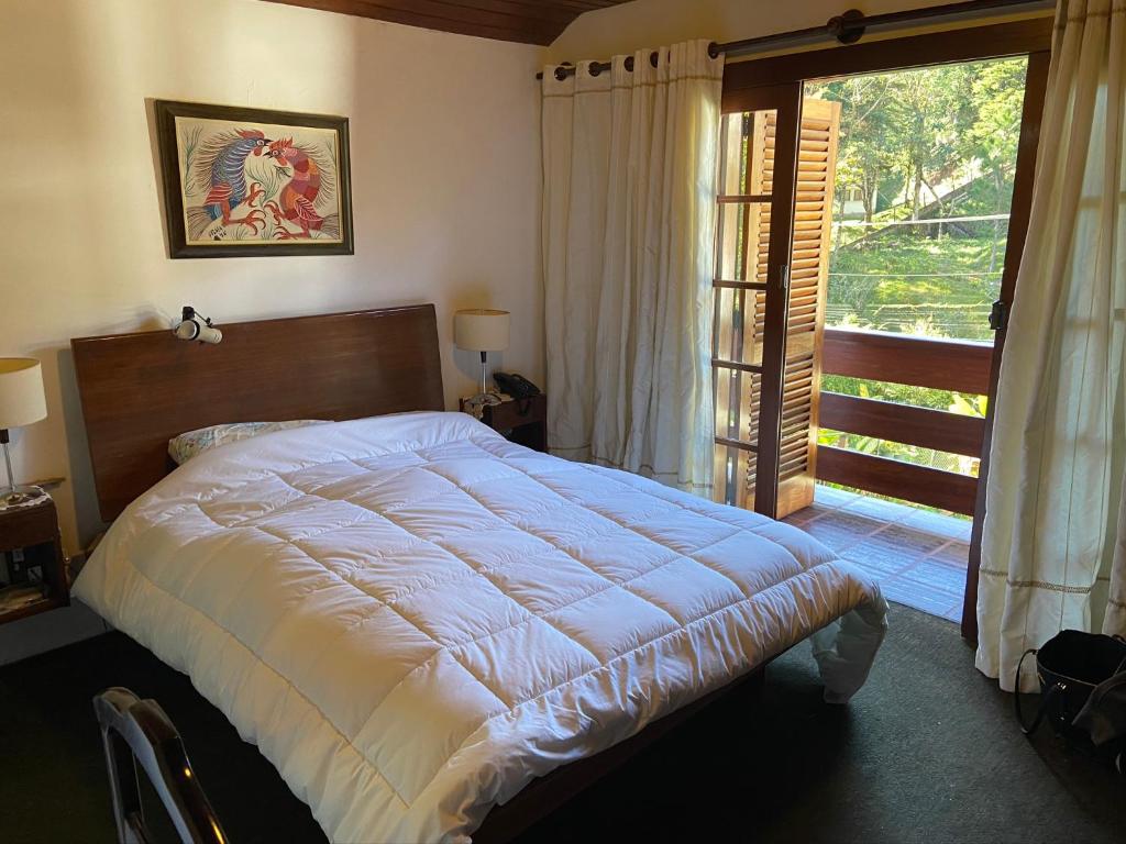 a bedroom with a large bed and a large window at Casa encantadora na serra-Teresópolis in Teresópolis