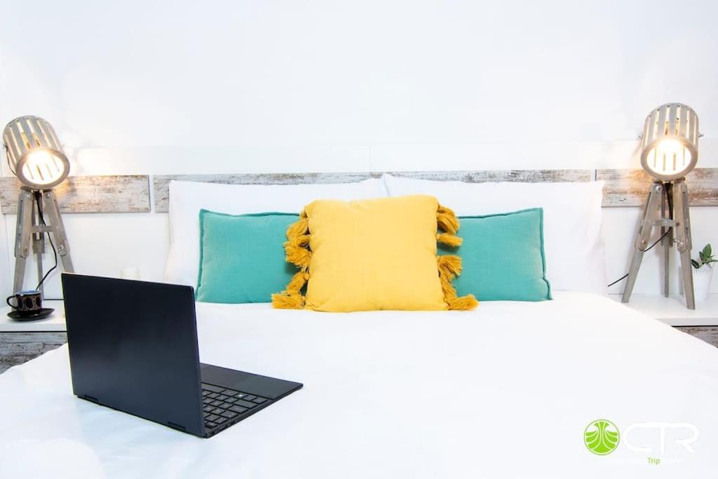 einen Laptop auf einem Bett mit gelbem Kissen in der Unterkunft LARGE COMPLETE APARTMENT, In The Center With Balcony in Santiago de Compostela