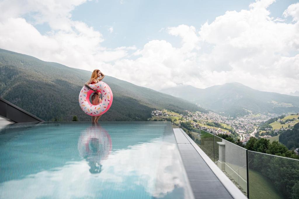 una mujer está sentada en un anillo de vida en una piscina en La Cort My Dollhouse - Adults Only, en Ortisei