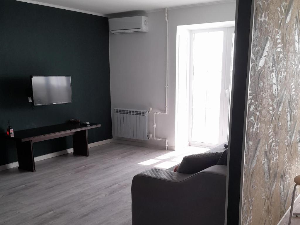 a living room with a couch and a television at Изумруд in Uralsk