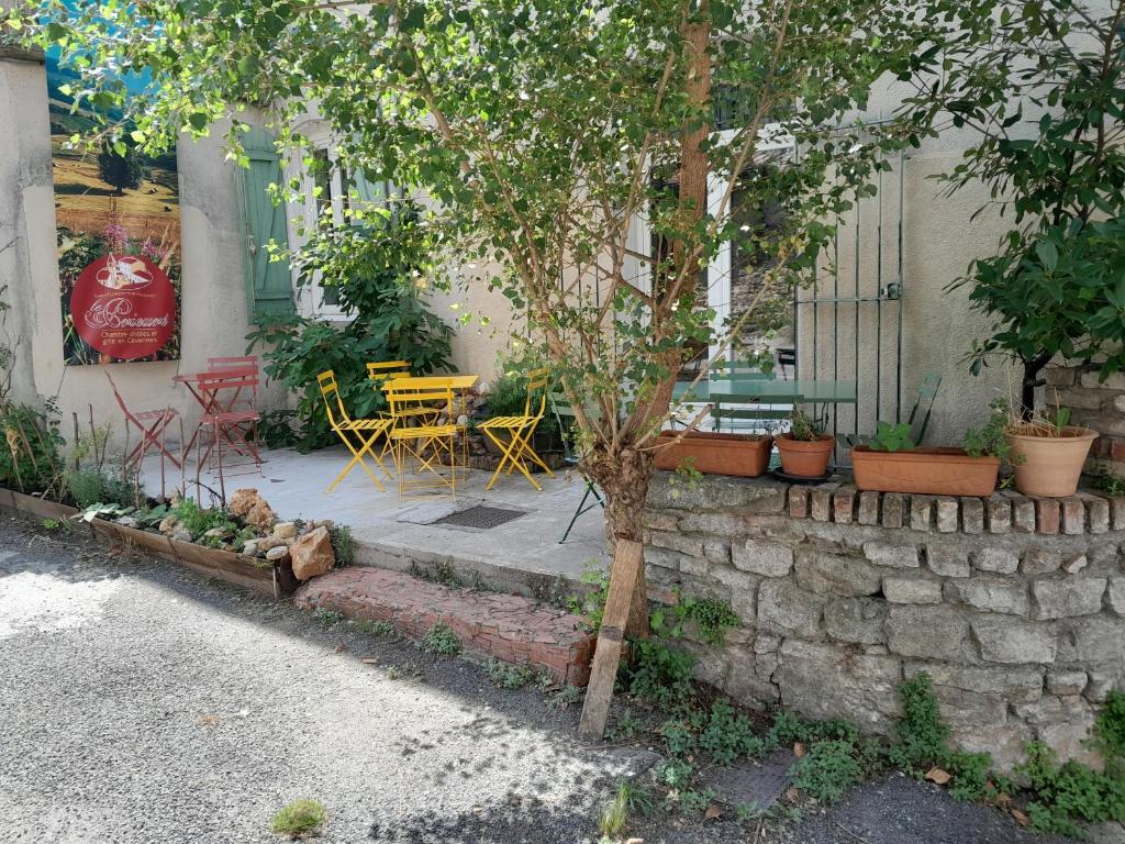 een patio met een tafel en stoelen en een boom bij LE PRIEURE in Saint-Florent-sur-Auzonnet
