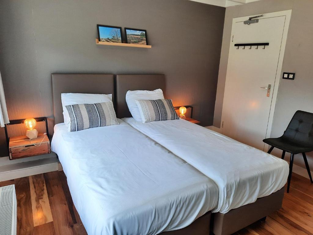 een slaapkamer met een bed met witte lakens en een stoel bij B & B Ayo in Wapserveen