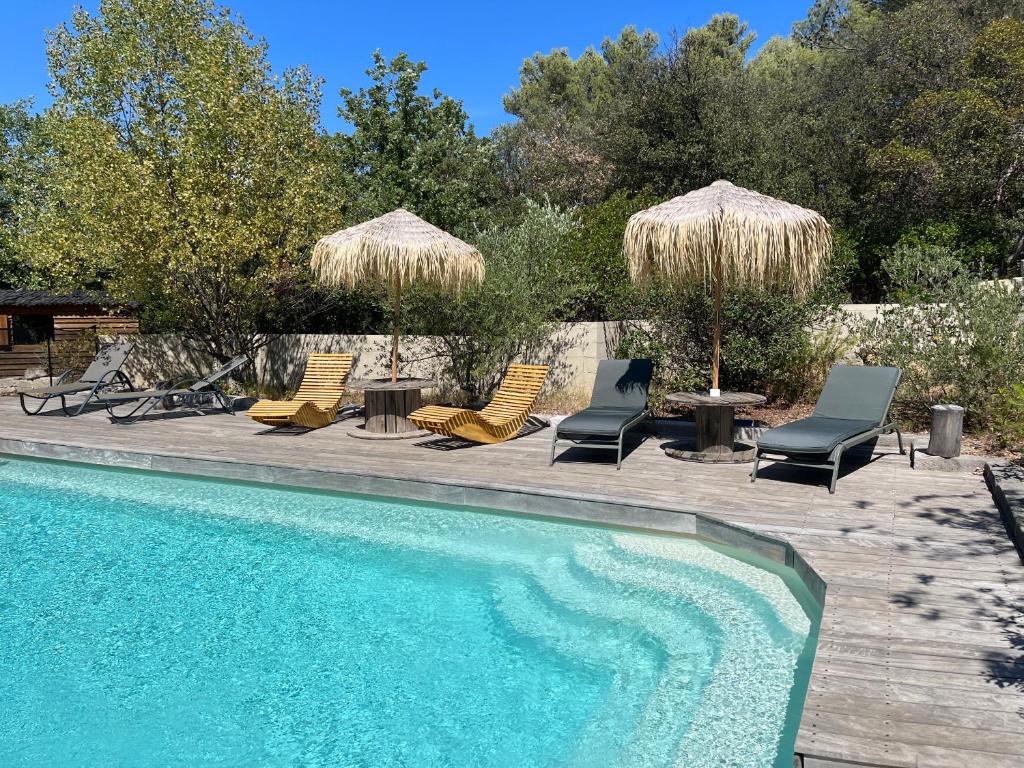 Auriol的住宿－La Maison Perchée，游泳池配有椅子和遮阳伞以及桌椅