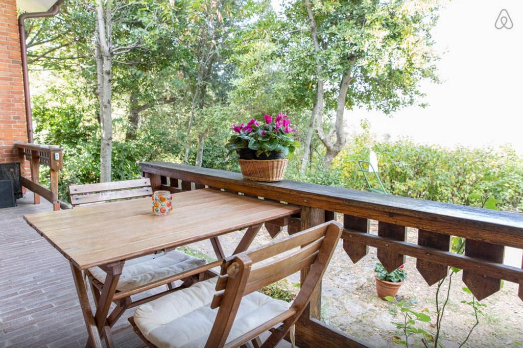 a wooden table and chairs on a deck with flowers at B&B La Baita in Aritzo