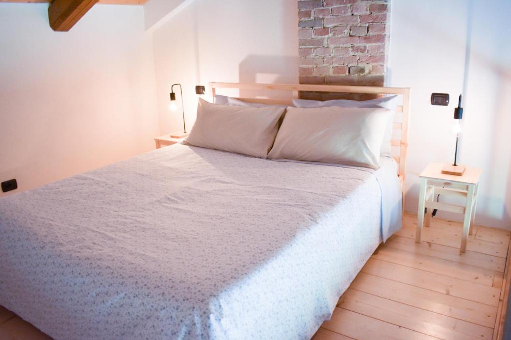 una camera con un letto bianco e un muro di mattoni di ROERooms a Vezza d'Alba