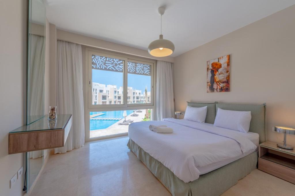 um quarto com uma cama grande e uma janela grande em High Standard 2-Bedroom in Mangroovy Residence, Pool View & Beach em Hurghada