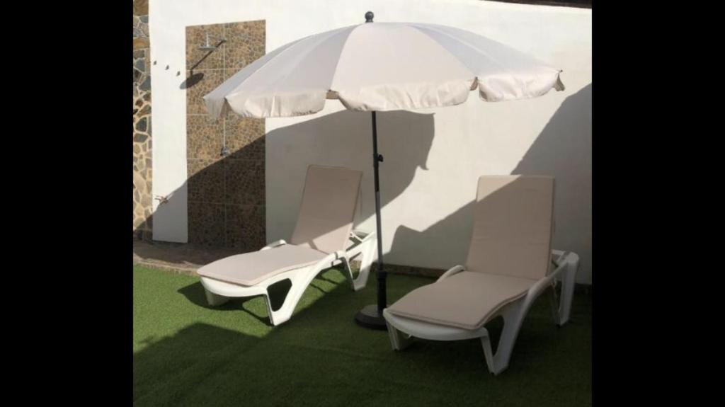 dwa krzesła i parasol na trawniku w obiekcie Jaye’s Home w Aronie
