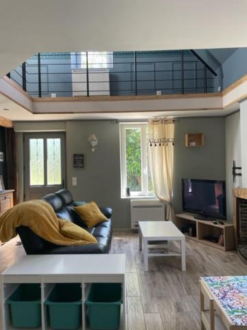 a living room with a couch and a tv at Le Jardin de Juliette in Gournay