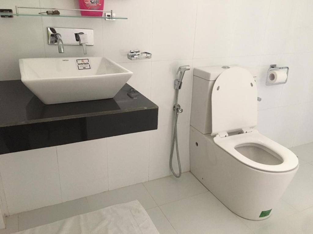 a bathroom with a white toilet and a sink at Lush Green Villa in Talpe