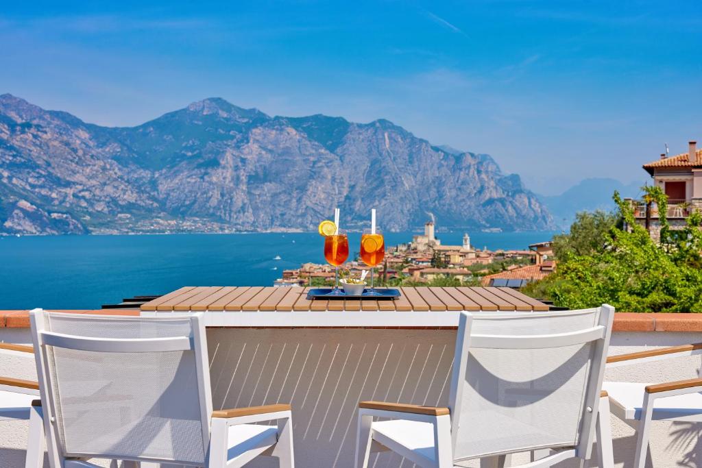Hotel Villa Smeralda في مالسيسيني: طاولة مع اثنين من المشروبات على رأس شرفة مع الجبال