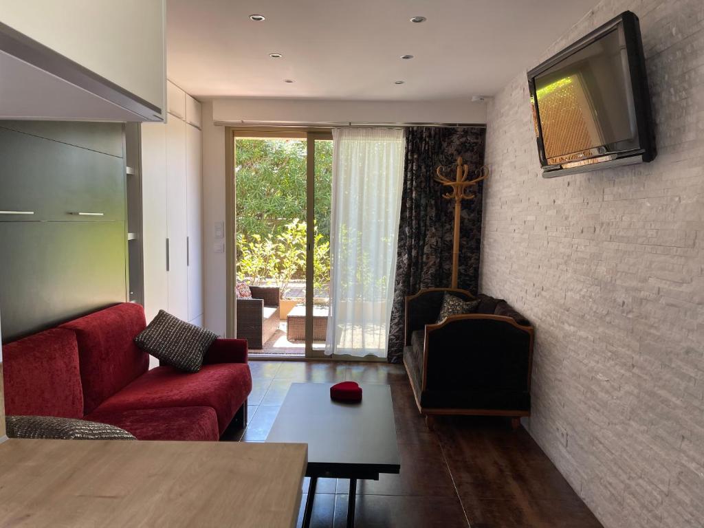 un soggiorno con divano rosso e TV a parete di Studio dans résidence privée à 15 mn de cannes a Le Cannet