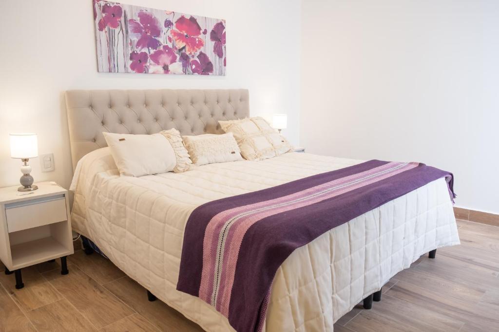 a bedroom with a large bed with a purple blanket at Augusta Deluxe in Salta