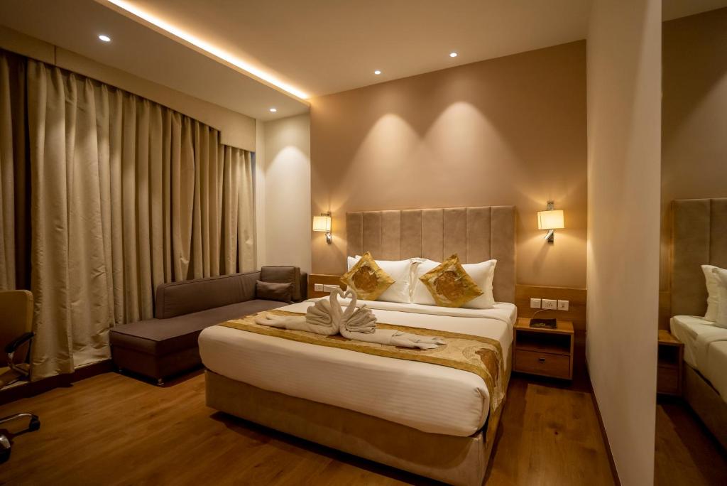 a hotel room with a bed and a couch at Celebrant Hotel in Varanasi