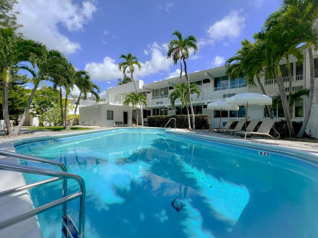 a large swimming pool with palm trees in front of a building at Beach Gardens in Fort Lauderdale