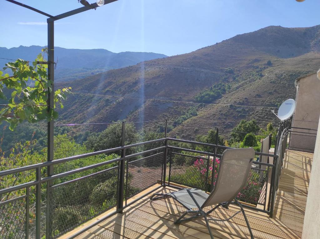 una silla en el balcón con vistas a la montaña en Maison de village avec vue sur les montagnes en Bigorno