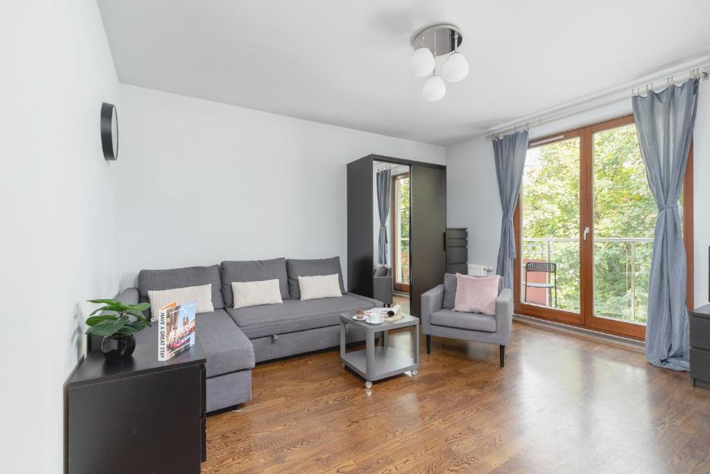 uma sala de estar com um sofá cinzento e uma cadeira em Cracow Skałki Twardowskiego Tyniecka by Renters em Cracóvia