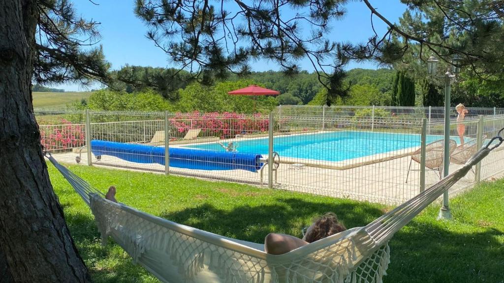 a person laying in a hammock next to a pool at Domaine de la Boissière in Marigny-Marmande