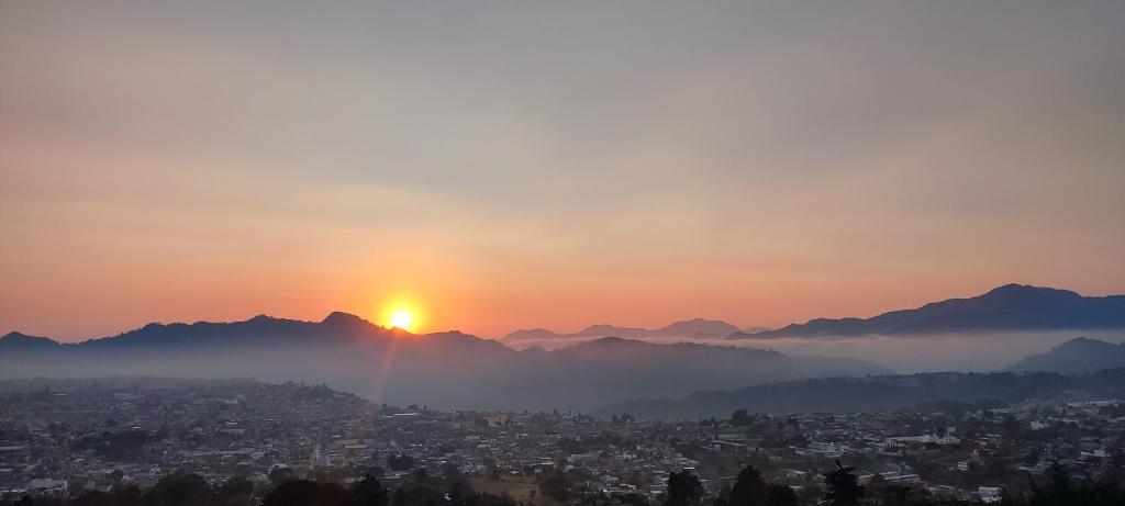 a view of a city with the sun setting behind mountains at HOTEL ALTAVISTA in Zacatlán