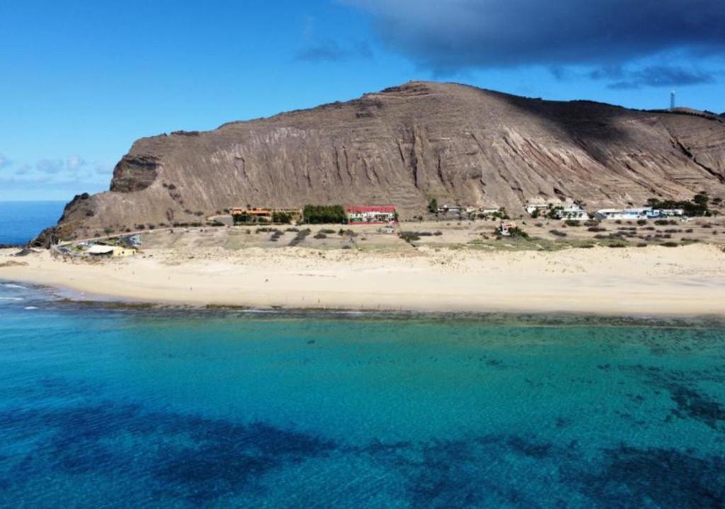 an island in the ocean next to a mountain at Porto Santo Destination in Porto Santo
