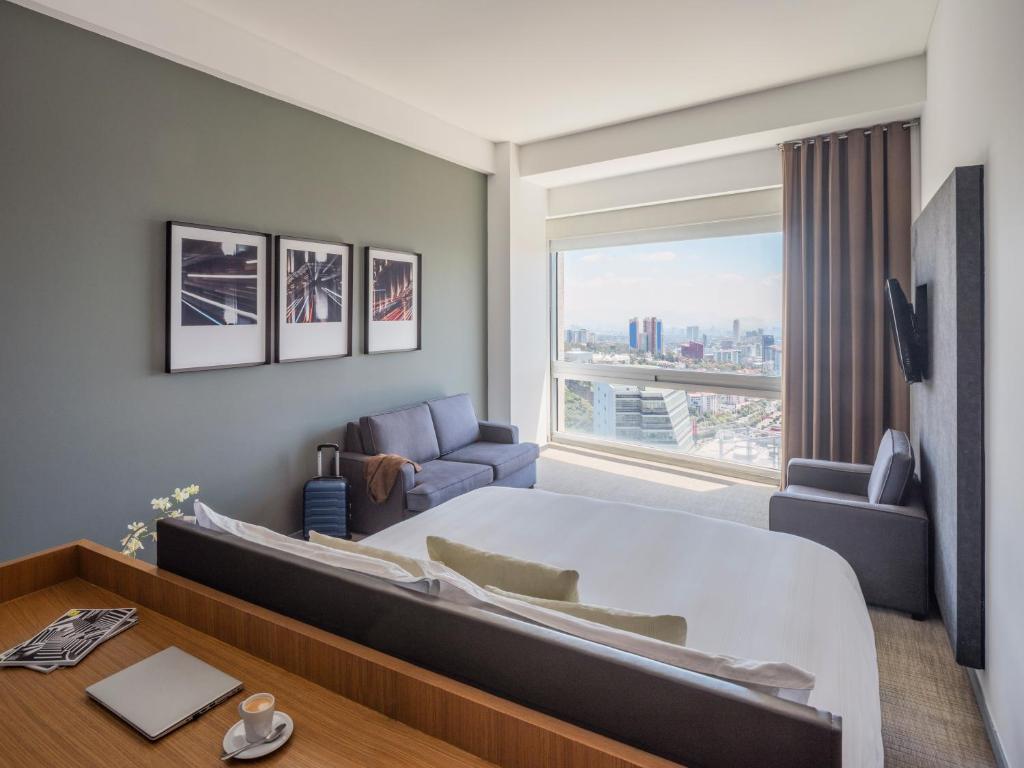 a bedroom with a large bed and a large window at The Paragon Hotel Mexico Santa Fe By Accor in Mexico City
