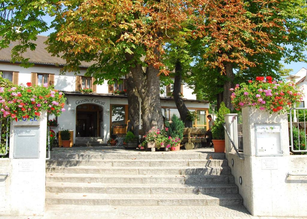 a tree in front of a building with stairs and flowers at Hotel Gasthof Groß in Bergkirchen