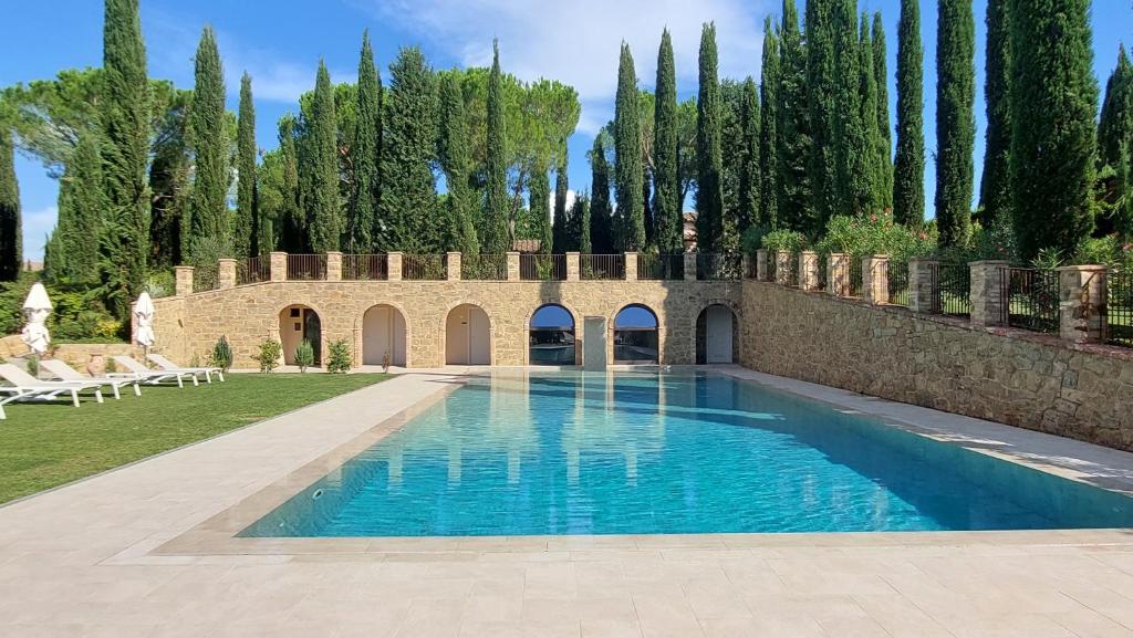 una piscina frente a un edificio con árboles en Tenuta Tegolato, en Barberino di Val d'Elsa