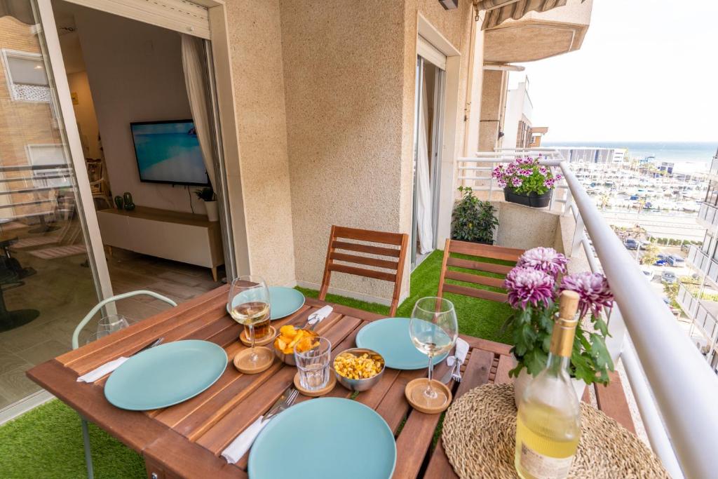 einen Holztisch mit Tellern und Weingläsern auf dem Balkon in der Unterkunft NUEVO a estrenar. Vistas al mar, terraza, ascensor in Santa Pola
