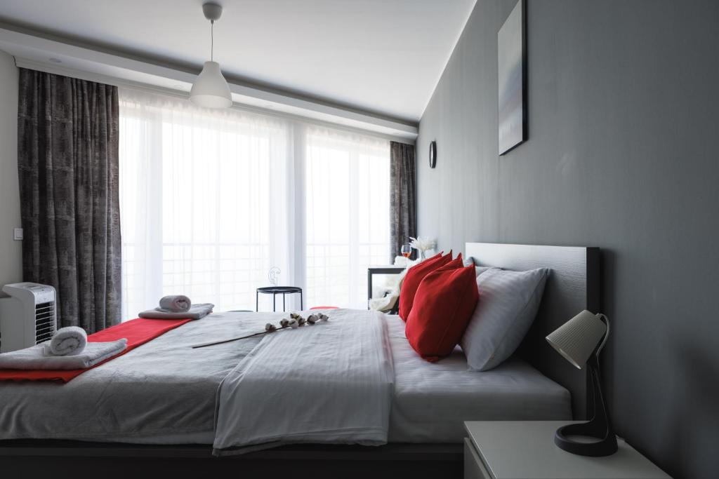 sypialnia z dużym łóżkiem z czerwonymi poduszkami i oknem w obiekcie Horizont Dedine w mieście Golubac