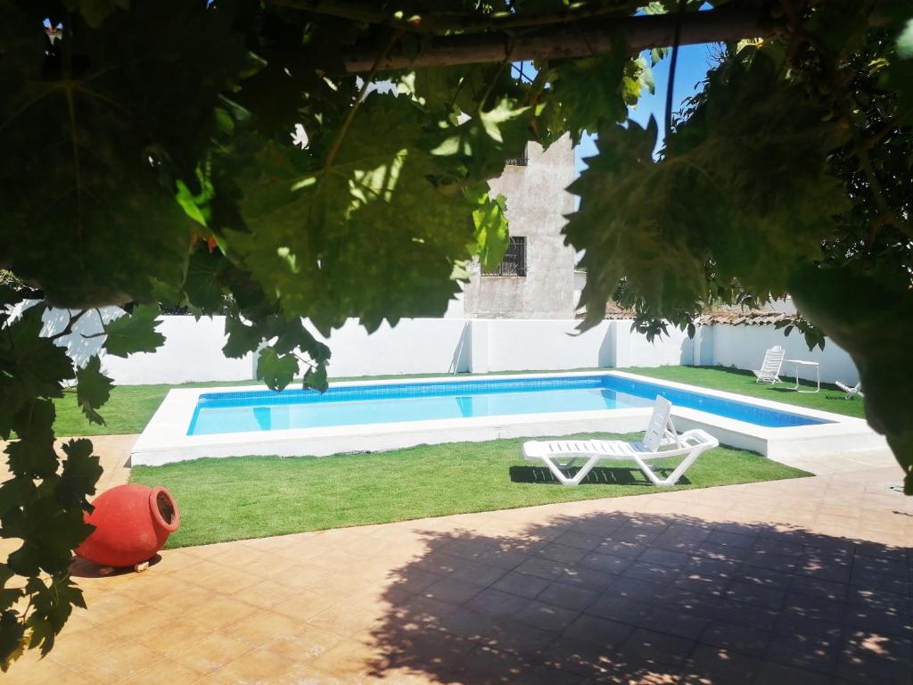 einen Pool mit einem weißen Stuhl und einer Bank in der Unterkunft Sierra de Aracena Cala Huelva in Cala