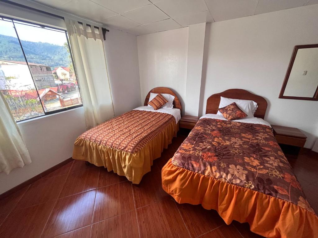 2 Betten in einem Zimmer mit Fenster in der Unterkunft Hospedaje Familiar Laos in Oxapampa