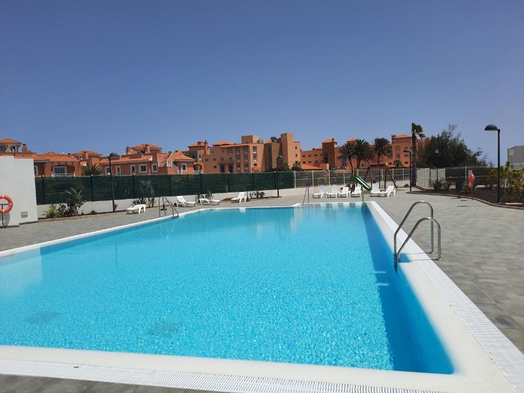 une grande piscine bleue avec des bâtiments en arrière-plan dans l'établissement Sol y Luz 2, à Caleta de Fuste