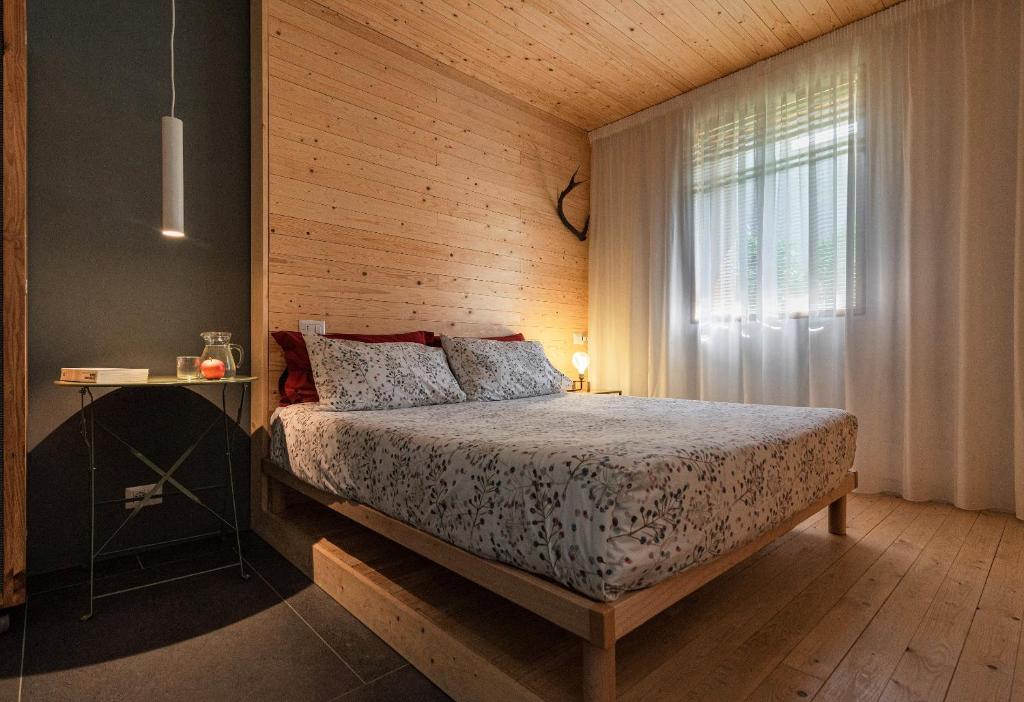 a bedroom with a bed with a wooden wall at Maison 4 jardin - Casa design ai margini del bosco in Crodo
