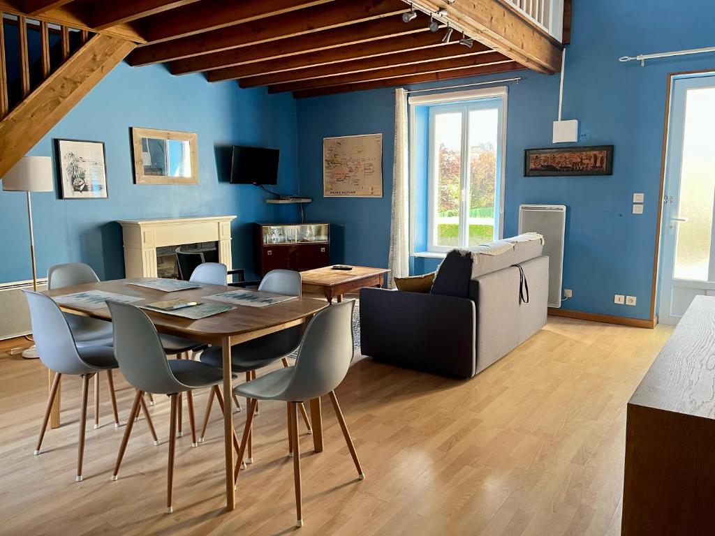 ein Esszimmer mit einem Tisch und Stühlen sowie blauen Wänden in der Unterkunft L'hippocampe - appt mezzanine centre d'Arromanches in Arromanches-les-Bains