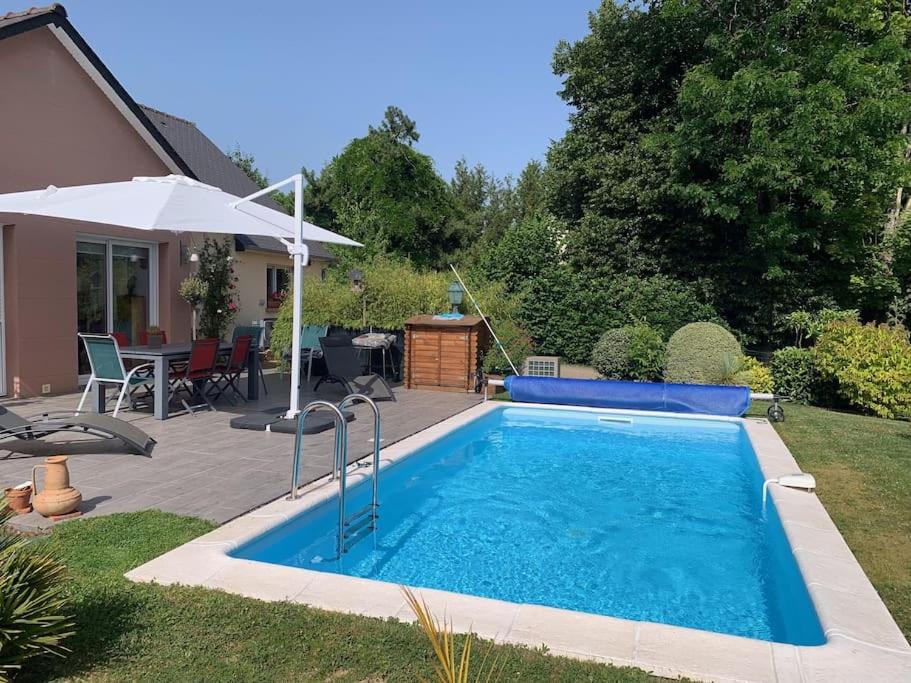 una piscina en un patio con sombrilla en Maudon Coeur de Baie, en Ponts