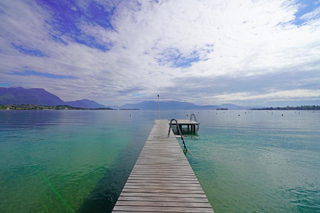 un muelle de madera en medio de una masa de agua en Appartamento Elena, en Manerba del Garda